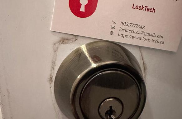LockTech car and home locksmith business card above a new deadbolt lock on residential door.
